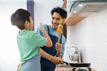 Asian man with young son are enjoy cooking together in kitchen at home in weekend.
