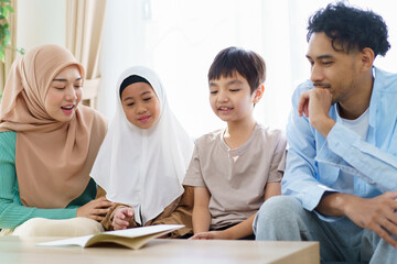 Cheerful - happy Asian muslim family relaxing together in living room.