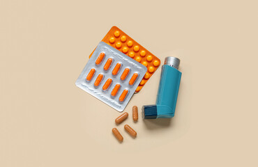 Asthma inhaler and pills on beige background