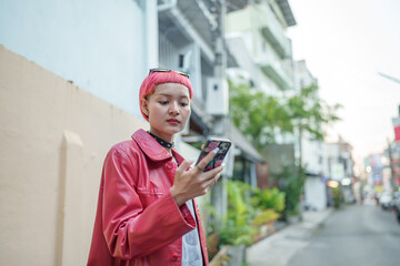Fototapeta premium Traveler Gen z girl leather fashion with punk Asian woman tourist&nbsp;in city street searching location in map application online smart phone using GPS&nbsp;navigating