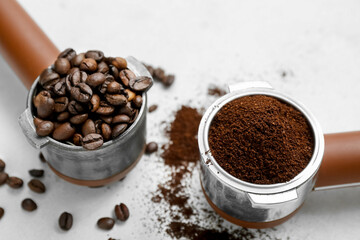 Portafilters with coffee beans and powder on light background
