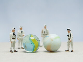 Naklejka premium Mini toy of action figure at outdoor with blurred background. Toy photography concept design. Minifigure of scientist character with marble stone. People wear hazmat suit.