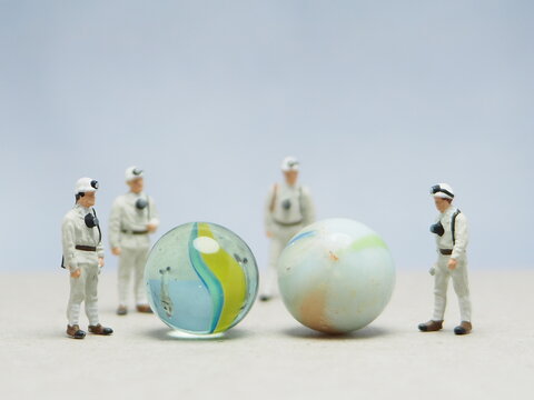 Mini toy of action figure at outdoor with blurred background. Toy photography concept design. Minifigure of scientist character with marble stone. People wear hazmat suit. - Powered by Adobe