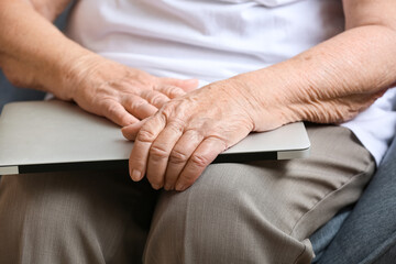 Senior woman with laptop sitting at home, closeup