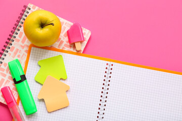 Obraz na płótnie Canvas Notebooks with fresh apple and different stationery on pink background