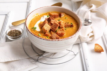 Bowl of tasty cream soup with croutons on white wooden background