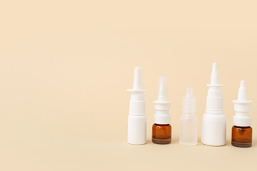 Bottles of nasal drops on beige background