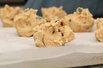 Close up of balls of uncooked chocolate chip cookie dough.