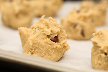Close up of balls of uncooked chocolate chip cookie dough.