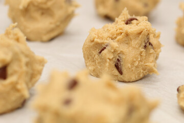 Close up of balls of uncooked chocolate chip cookie dough.