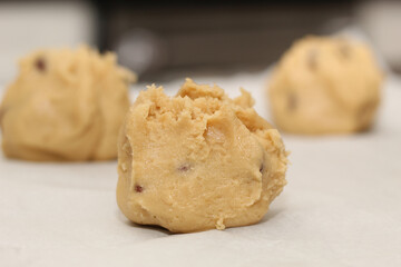 Close up of balls of uncooked chocolate chip cookie dough.