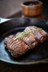 Grilled beef steak in a frying pan on a wooden background.