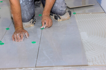 Worker meticulously places tiles on floor, ensuring precision careful alignment in renovation...