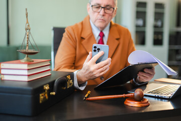 justice and law concept. Male judge in a courtroom the gavel, working with smart phone and laptop...