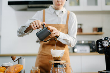 Closeup of barista brewing pour over coffee at home. Warm lifestyle concept featuring hand-crafted...