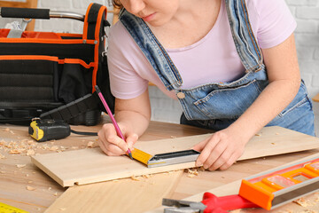 Female carpenter measuring plank width with square ruler in workshop, closeup