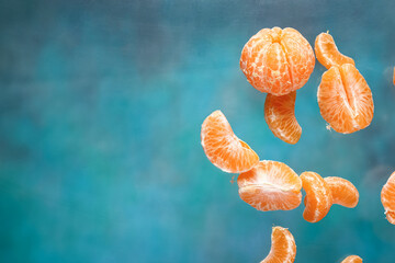 Flying sweet peeled mandarins on blue background
