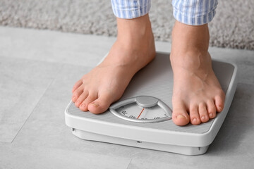Young woman standing on scales at home. Weight loss concept