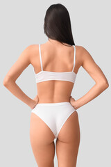 Young woman in white underwear on blue background, back view