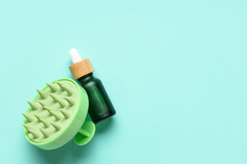 Hair scalp massager and bottle of cosmetic oil on blue background