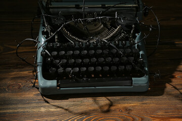 Vintage typewriter with barbed wire on wooden background. Printing ban concept