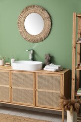 Modern sink with bath supplies on countertop near green wall in bathroom