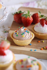 Delicious mini tarts with creamy toppings and colorful sprinkles, perfect for a party, celebration, or dessert spread