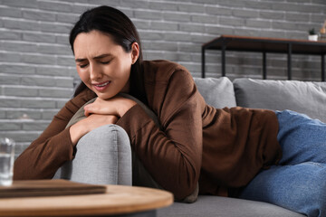 Obraz premium Depressed young woman crying on sofa at home