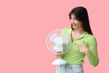 Young woman with electric fan on  pink background