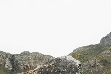 Flat design is illustrating large boulder on rugged hillside with moss patches under overcast sky