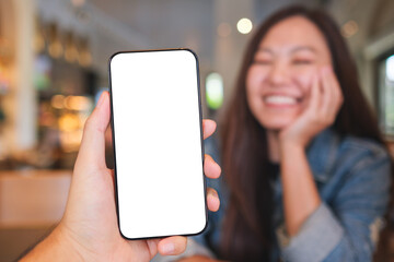 Mockup image of a man holding mobile phone with blank screen and a woman sitting in background