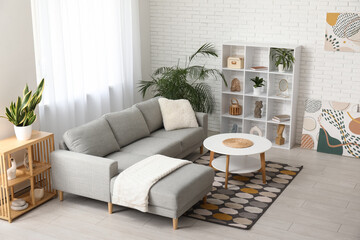 Interior of modern living room with grey sofa, shelving unit and coffee table