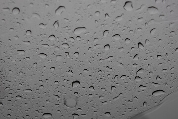 close-up, full-frame shot of numerous water droplets of varying sizes clinging to a glass surface