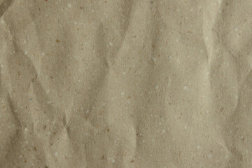 Close-up of a crumpled, light brown kraft paper texture. Its earthy tone