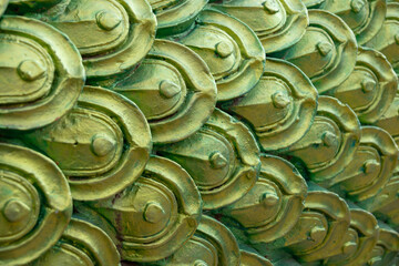 close-up of ornate, metallic green and gold scales, reminiscent of a dragon or the mythical Naga serpent in Thai art.