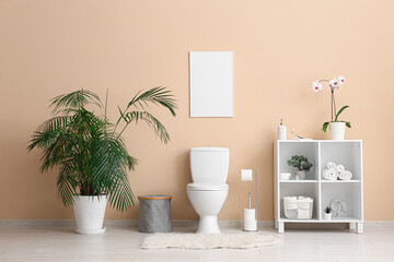Interior of modern restroom with toilet bowl, shelving unit with orchid and houseplant