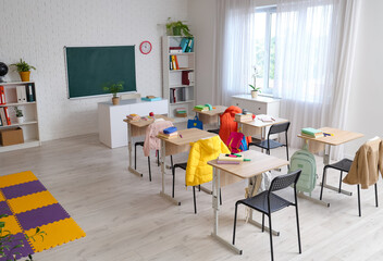 Interior of classroom with chalkboard, shelf units and desks