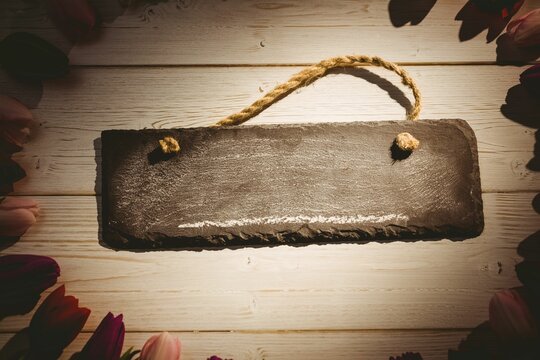 Fototapeta Flat design slate sign with frayed rope handle is lying on whitewashed planks with tulip border