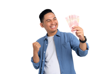 Excited young Asian man in casual shirt holding money and clenching fist, celebrating financial success isolated on transparent background