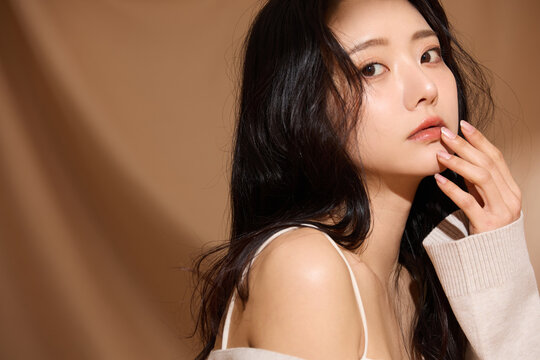 ベージュの布地背景で撮影をした若い女性の高級感のある美容ポートレート