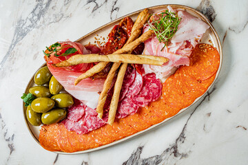A vibrant platter of cured meats, olives, and crispy breadsticks awaits