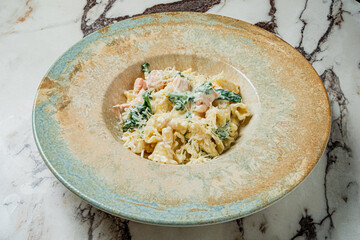 A vibrant dish featuring creamy pasta tossed with fresh salmon and greens on a stunning plate