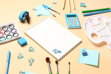 Paint palette, watercolor paints and different stationery on beige background, closeup