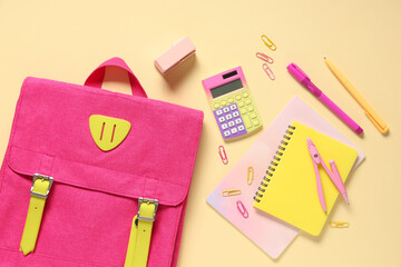 School backpack and different stationery on beige background