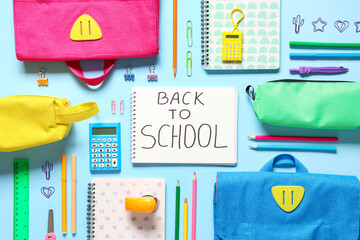 School backpacks, notebook with text BACK TO SCHOOL and different stationery on blue background