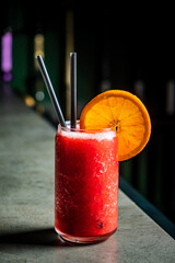 A vibrant cocktail with fresh strawberries and oranges, served chilled with steel straws