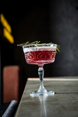 A captivating cocktail, adorned with rosemary, awaits enjoyment in a modern bar setting