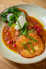 Golden fritters atop rich sauce, garnished with radishes, herbs, and cream, invite taste