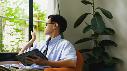 Asian man working by open window with natural light.