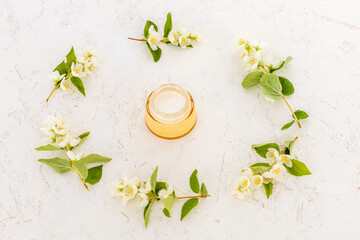 Body care products and branches of jasmine on the white background.
